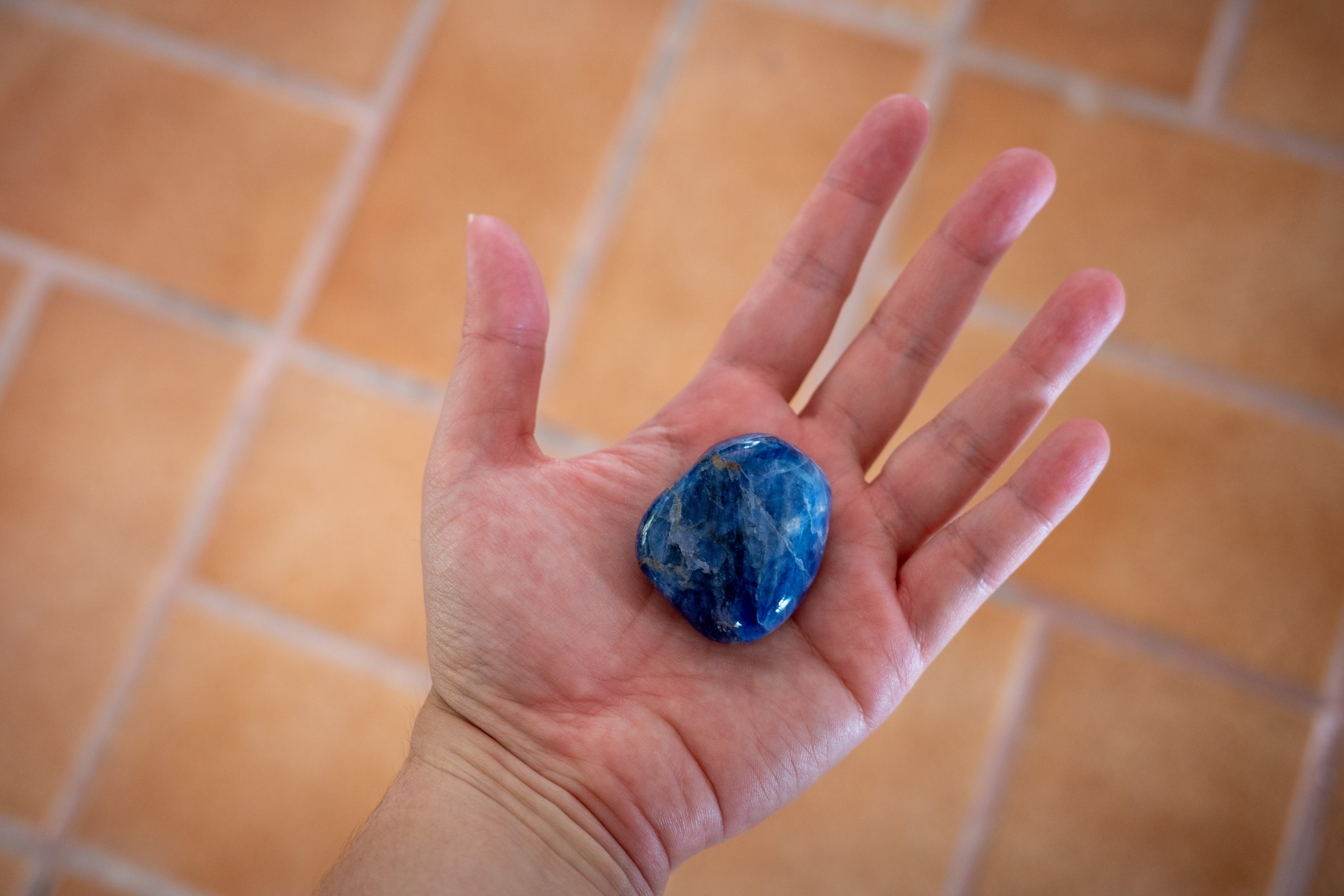 An open palm facing upwards with a piece of Sodalite stone in it