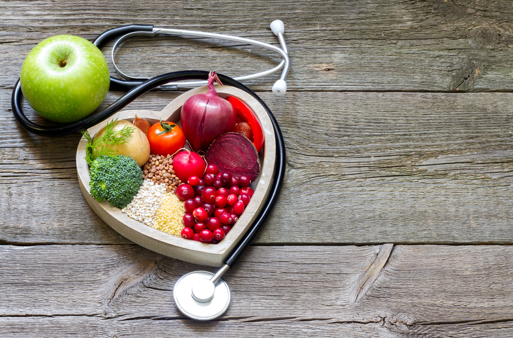 Fruit and vegetables in a heart shaped bowl with a stethoscope next to it