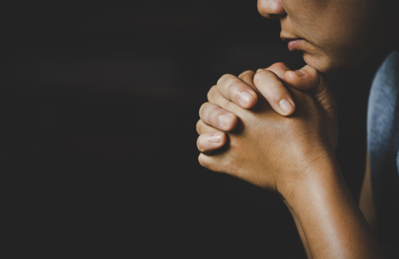 close up of woman praying in dark room