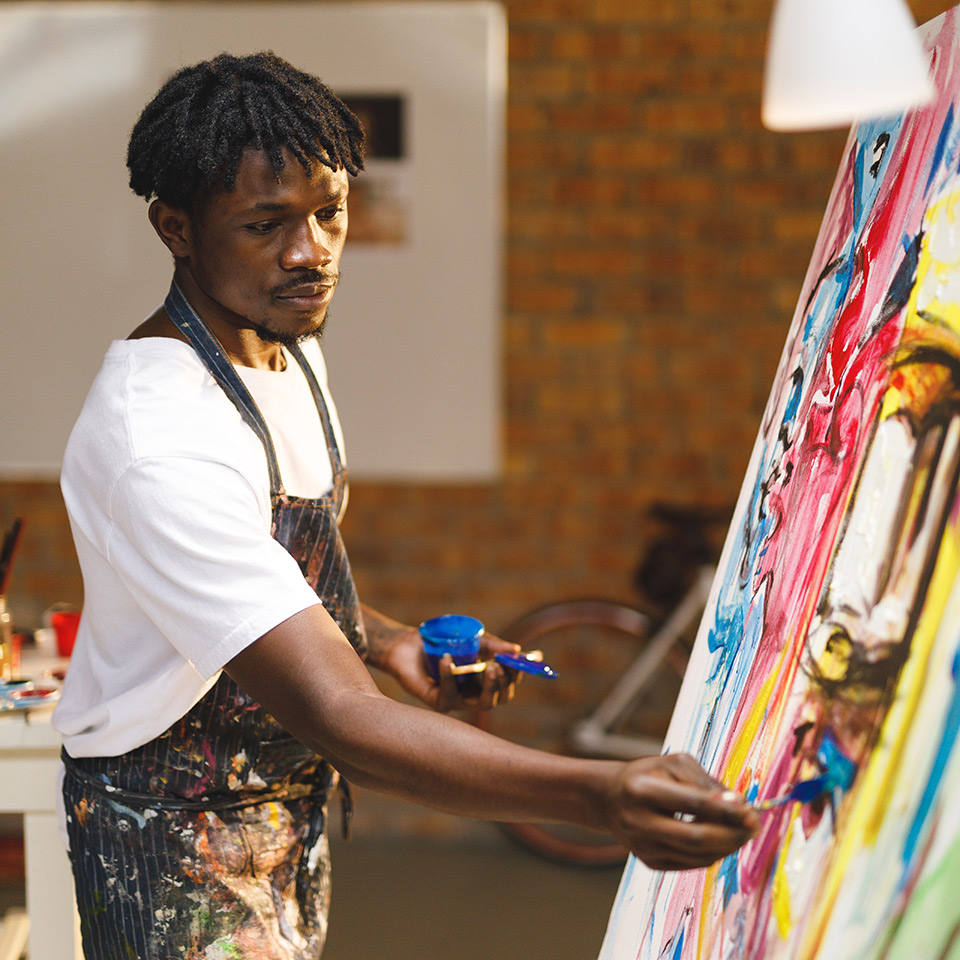 Painter at work painting with acrylics on canvas in an art studio.