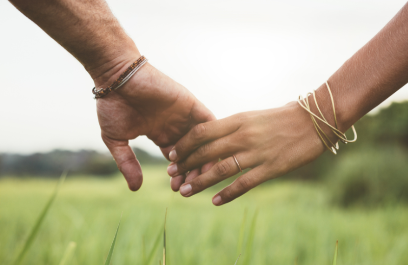 couple holding hands in field