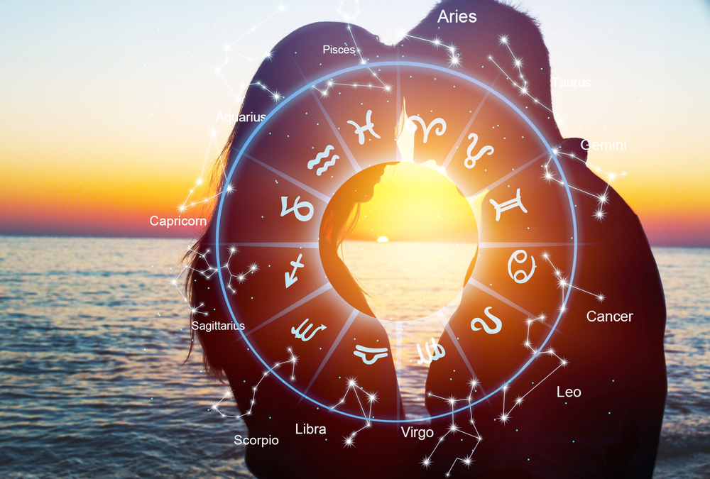 A couple in front of the sunset with a Zodiac wheel on top of them