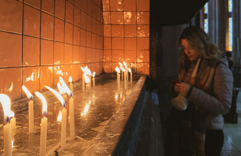 Woman praying near Church candles