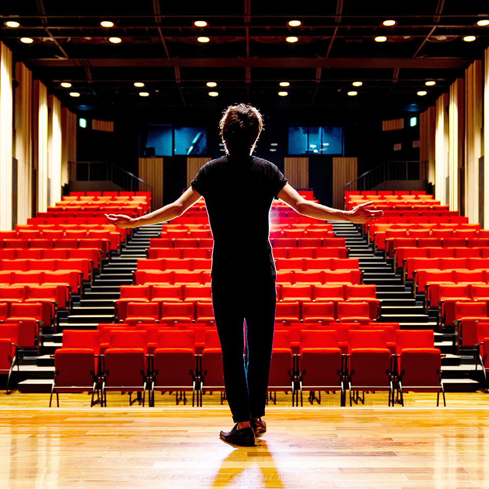 Young actor standing on the stage of a theatre.