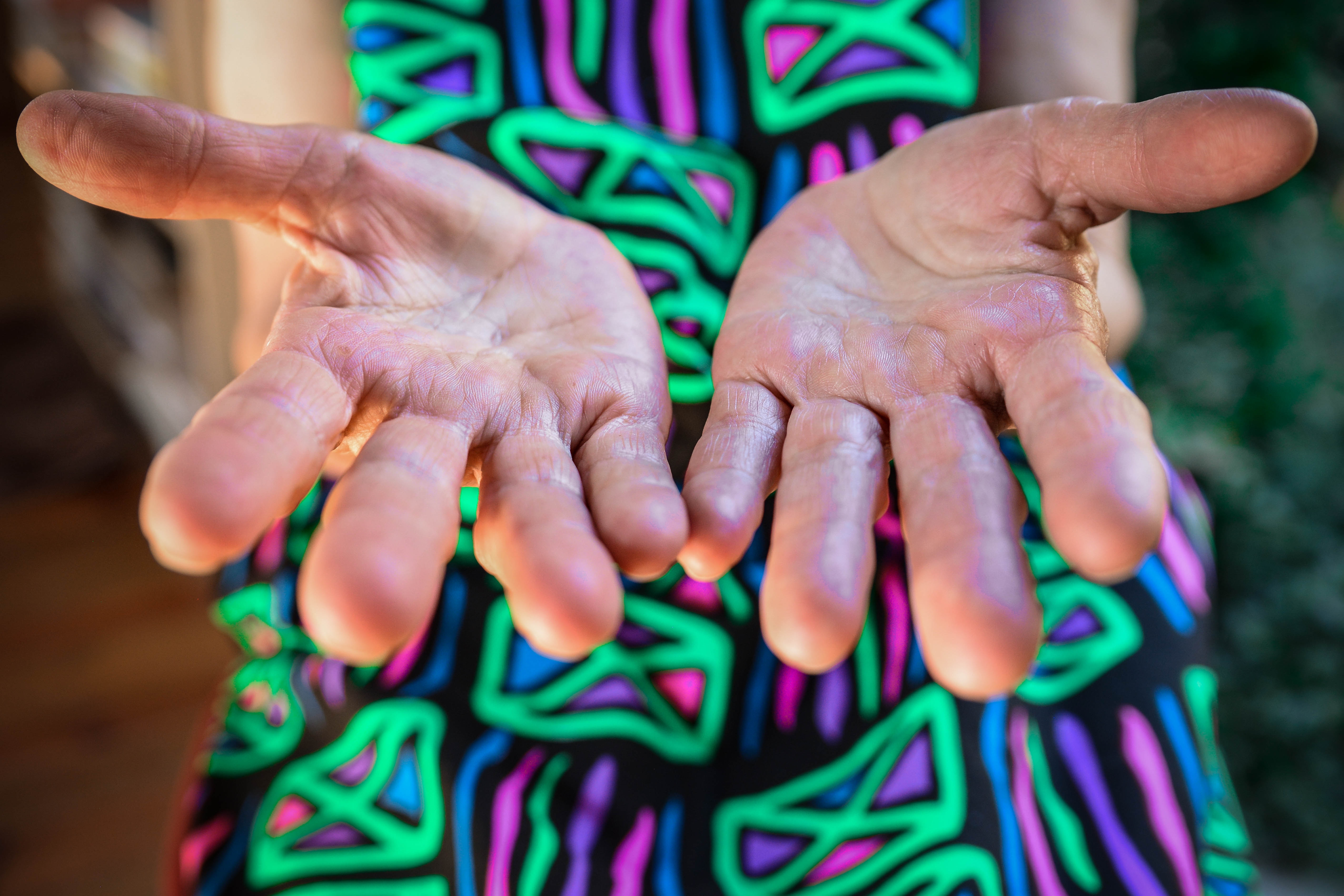 A woman with a brightly coloured dress holding out here hands.