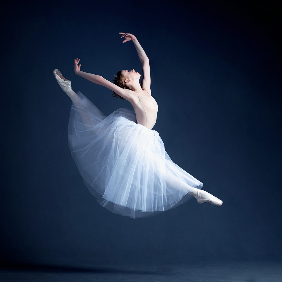 Pointe (ballet) shoes on a white tutu in a dance studio.