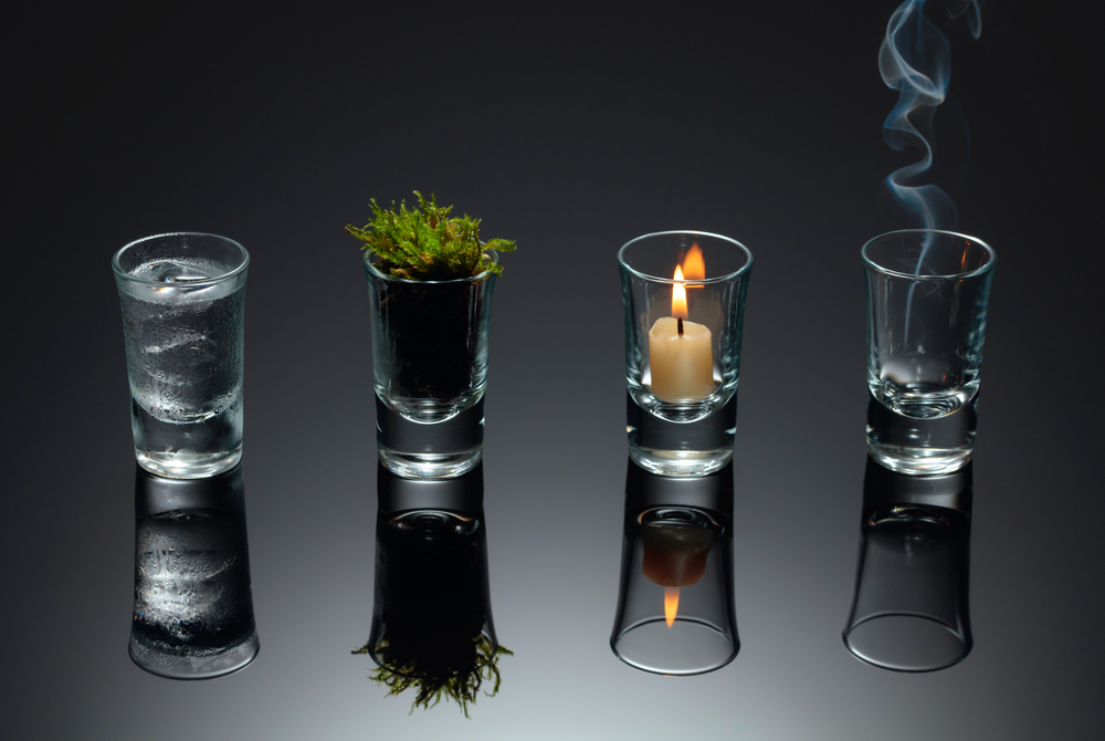 Four small glasses with each element inside - water, earth, fire and air