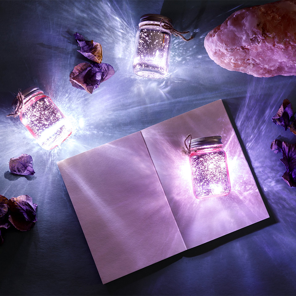 Open book surrounded by jars of glowing lights
