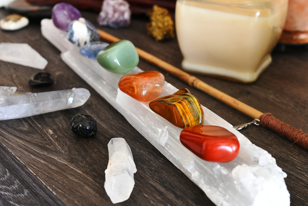 A close up image of seven chakra healing crystals charging on a selenite wand.