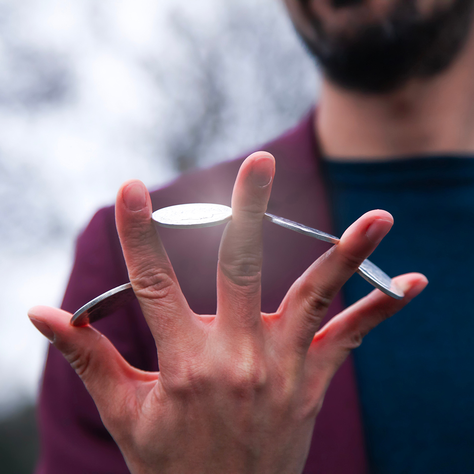Magician holding a coin between each finger of their hand