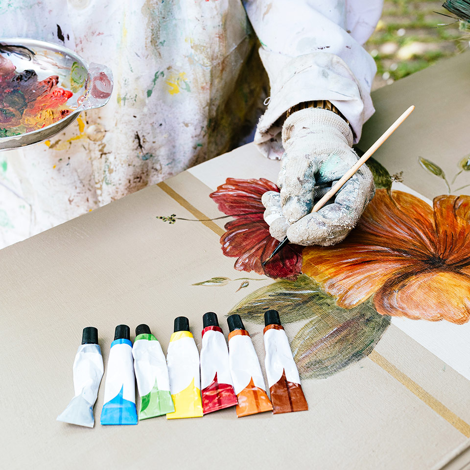 Person painting flowers with acrylic paints