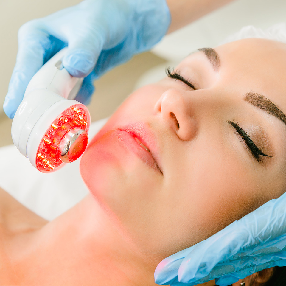 Woman receiving infrared cosmetic treatment on her face.