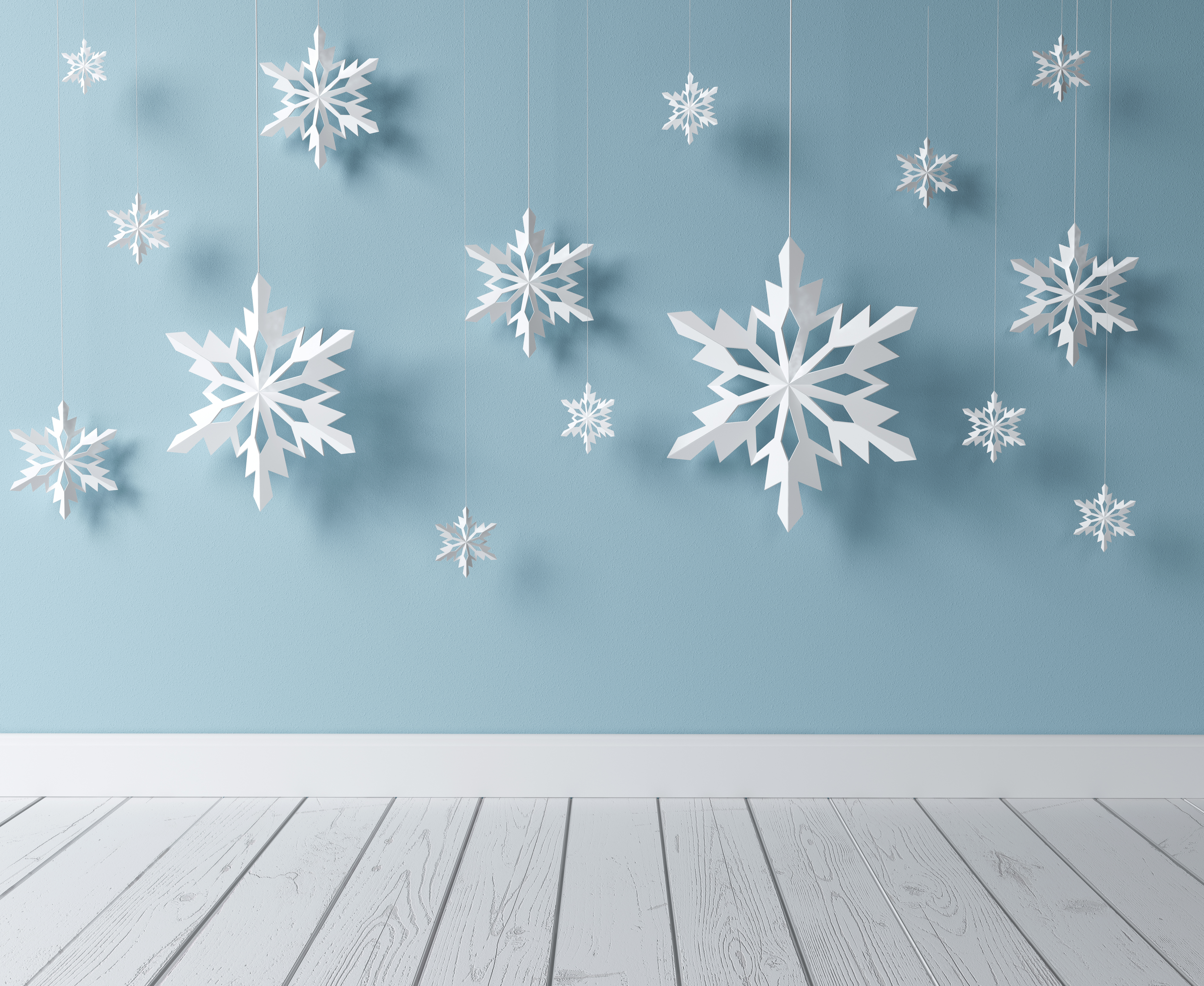 Homemade paper snowflakes against blue backdrop