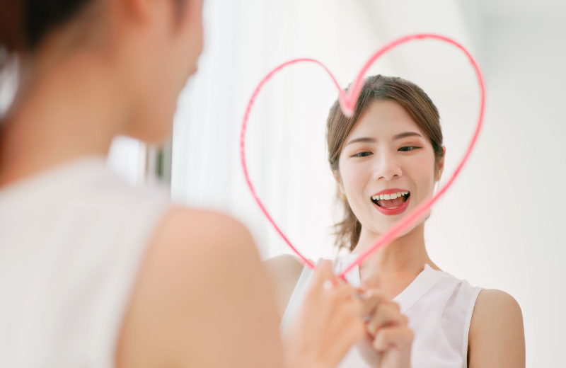 Image of a lady drawing a heart in the mirror.