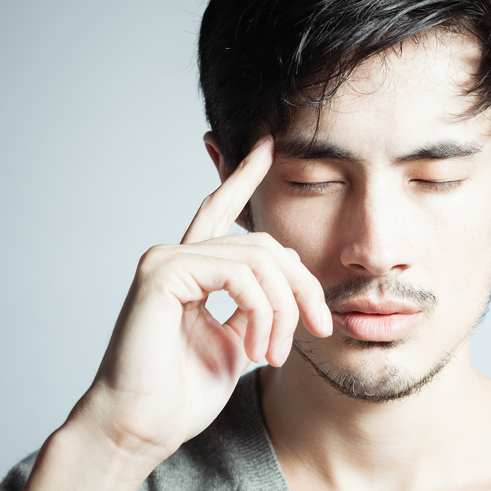 A man with his eyes closed whilst pointing to his head