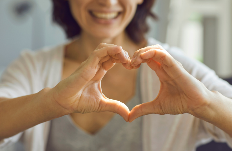 Image of someone making a love heart with their hands.
