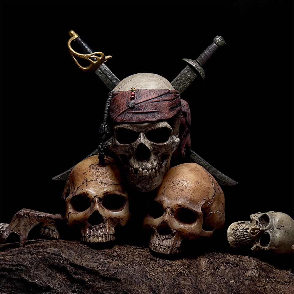 Still life with pirate skull with two swords and four human heads on a dark background