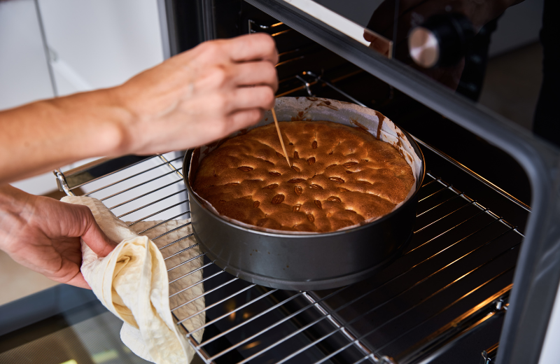 person checking cake is baked from oven