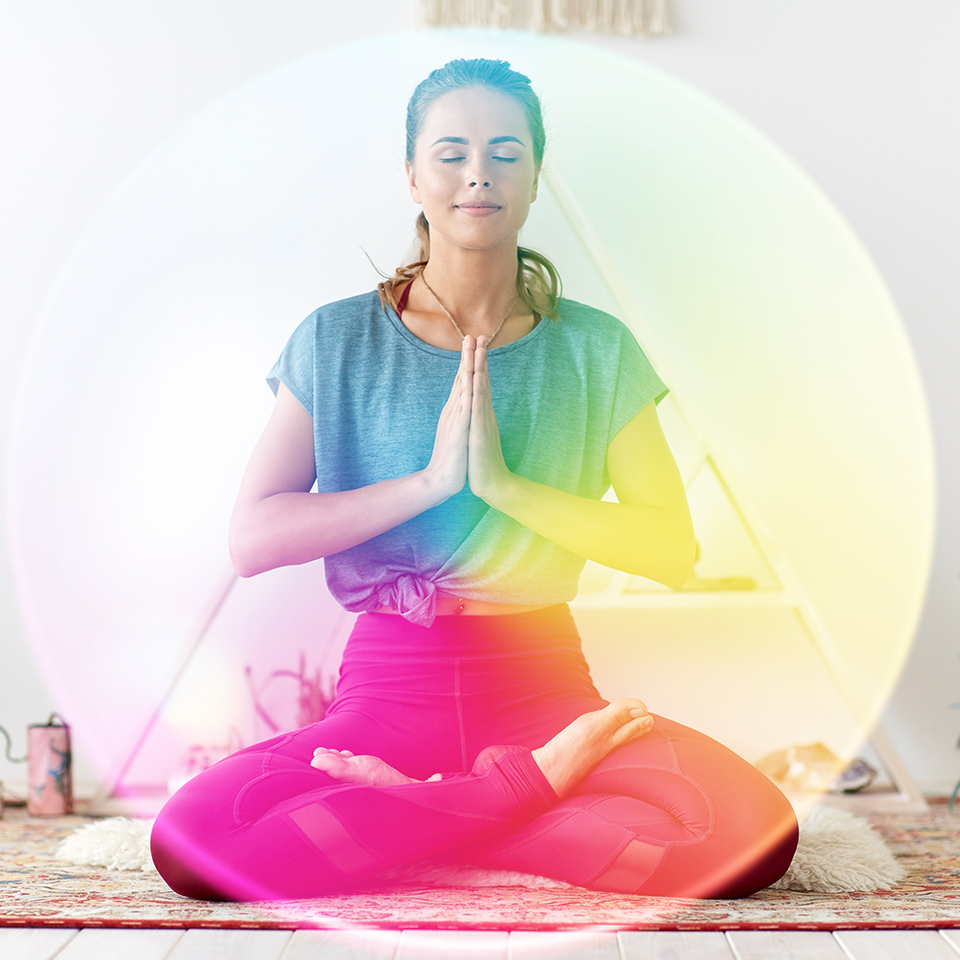 A meditating woman surrounded by a rainbow aura