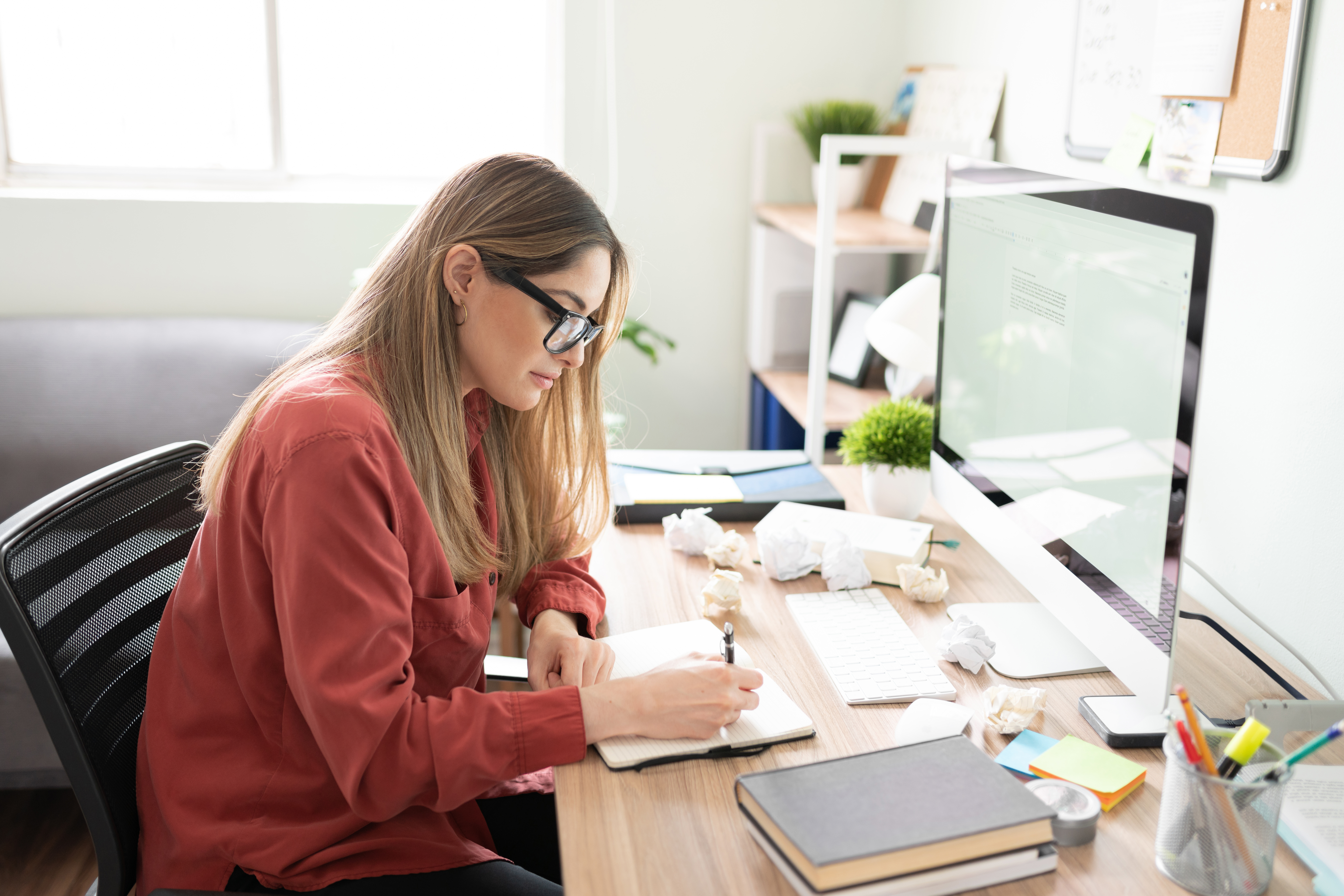 Woman with writer's block making notes next to her computer