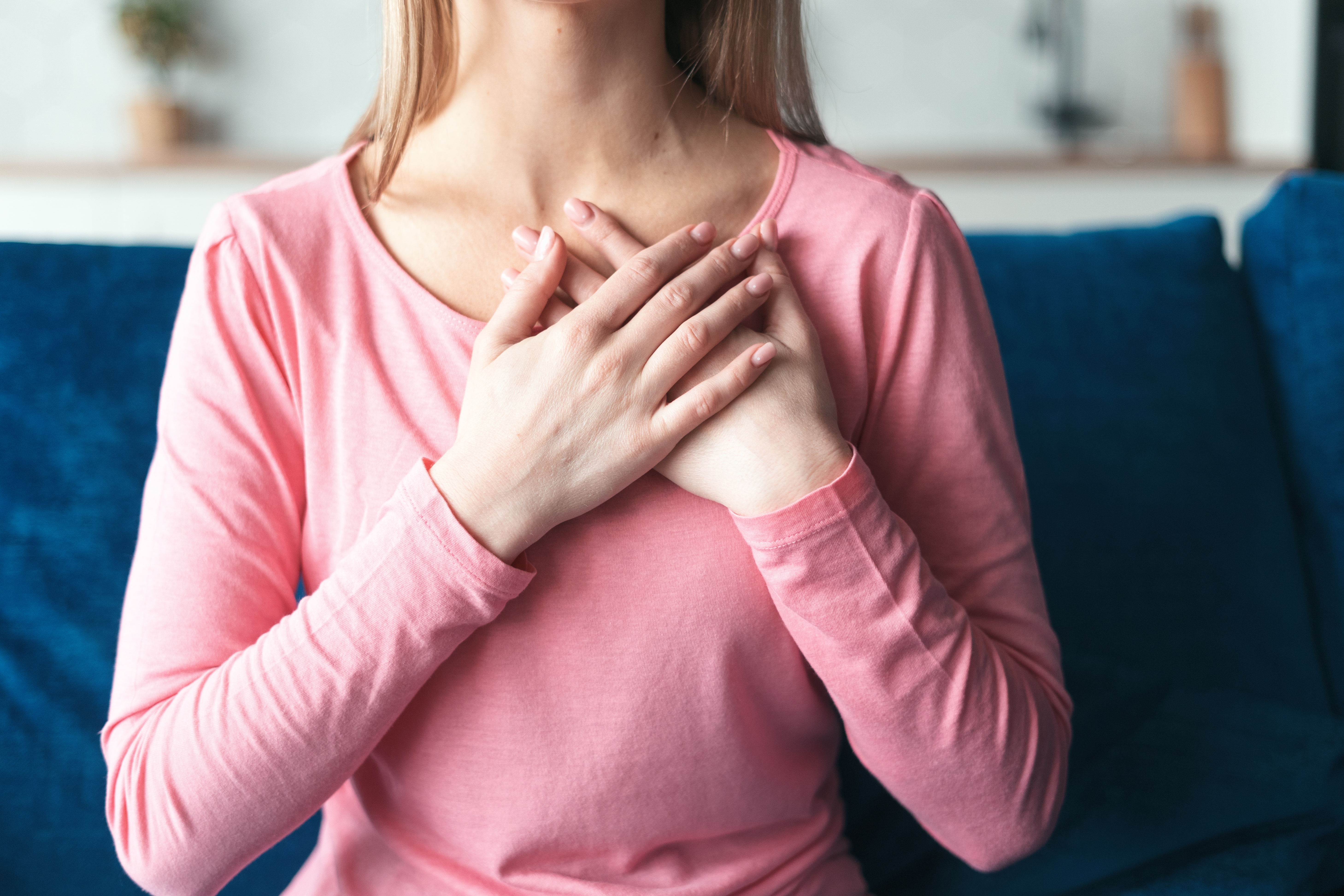 A woman with her two hands places on her heart