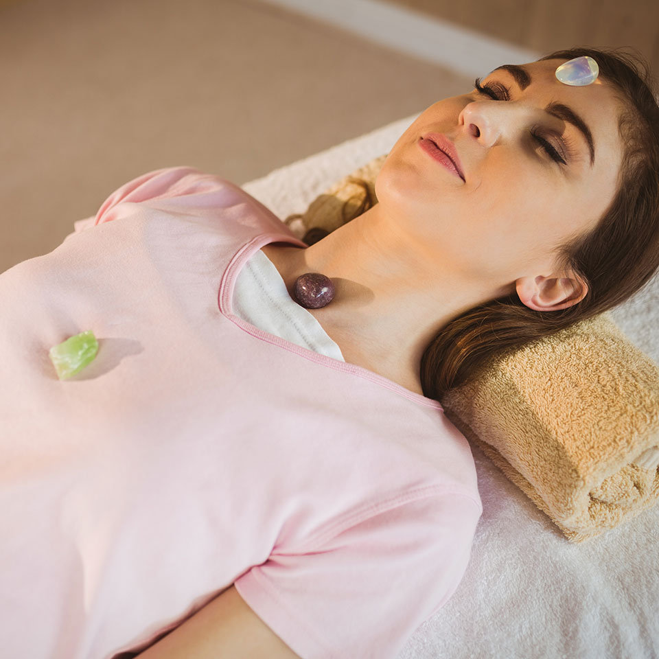 Advanced Crystal Healing - Woman lying down with crystals on chakra points as she receives crystal healing