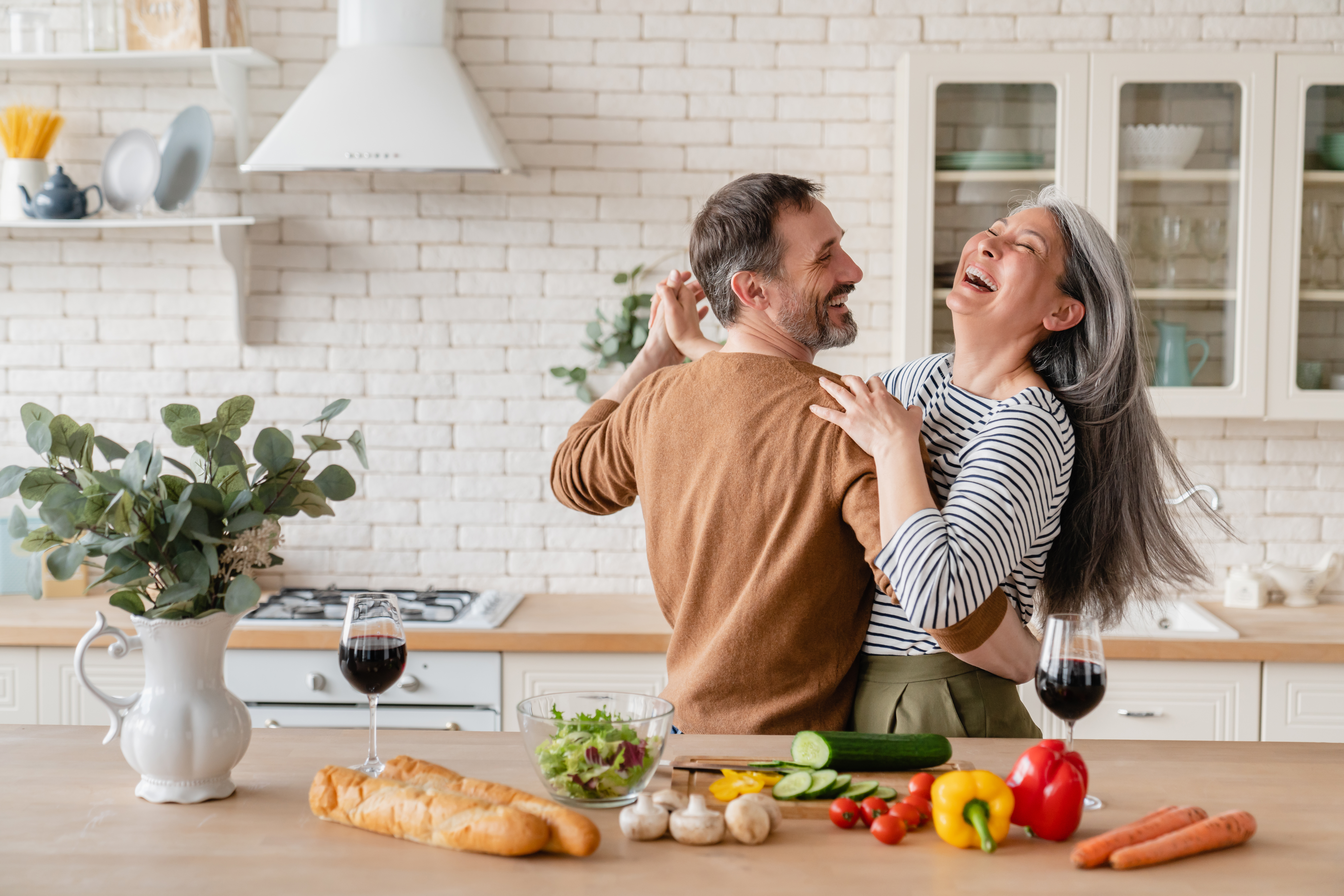 Energetic older couple dancing and laughing in kitchen