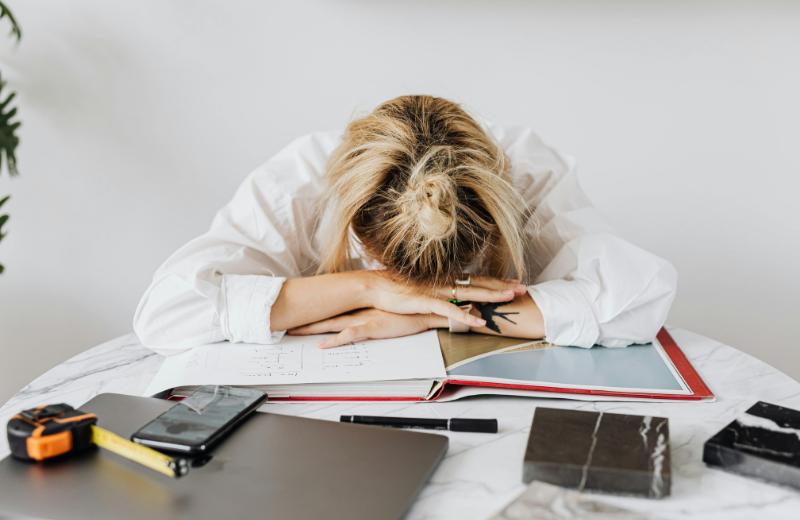 burned-out woman with head in hands at desk