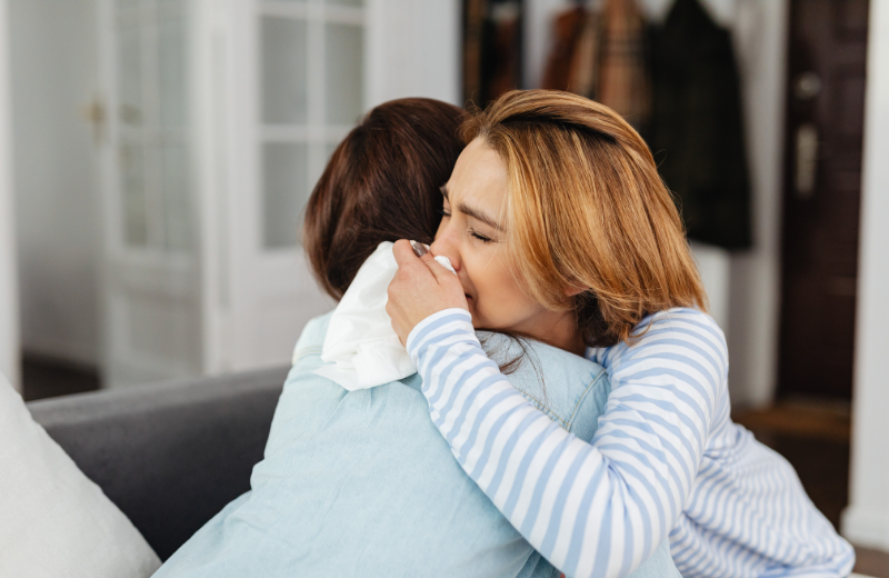 woman hugging another and crying
