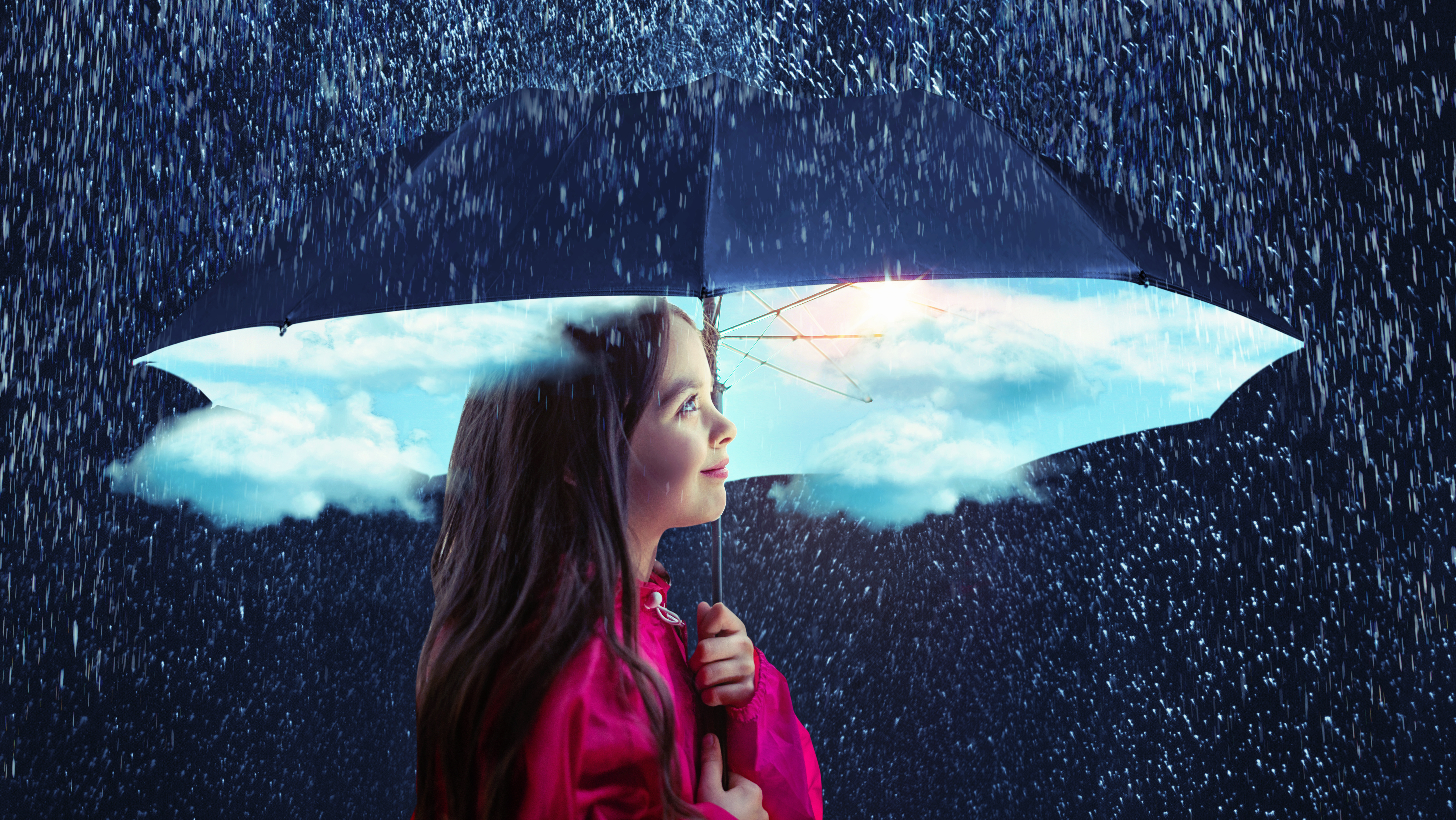 Little girl with an umbrella smiling in a storm