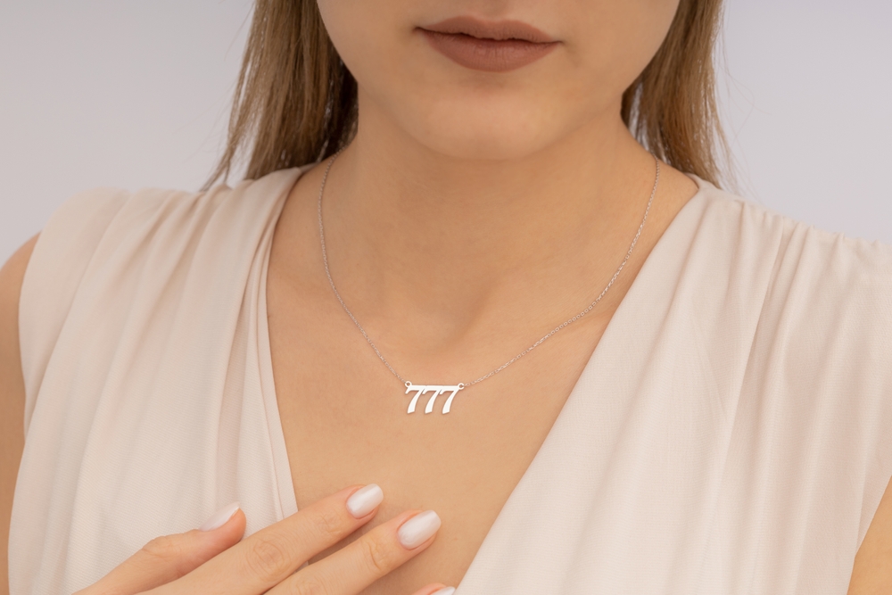 A woman wearing a silver necklace with '777' on it