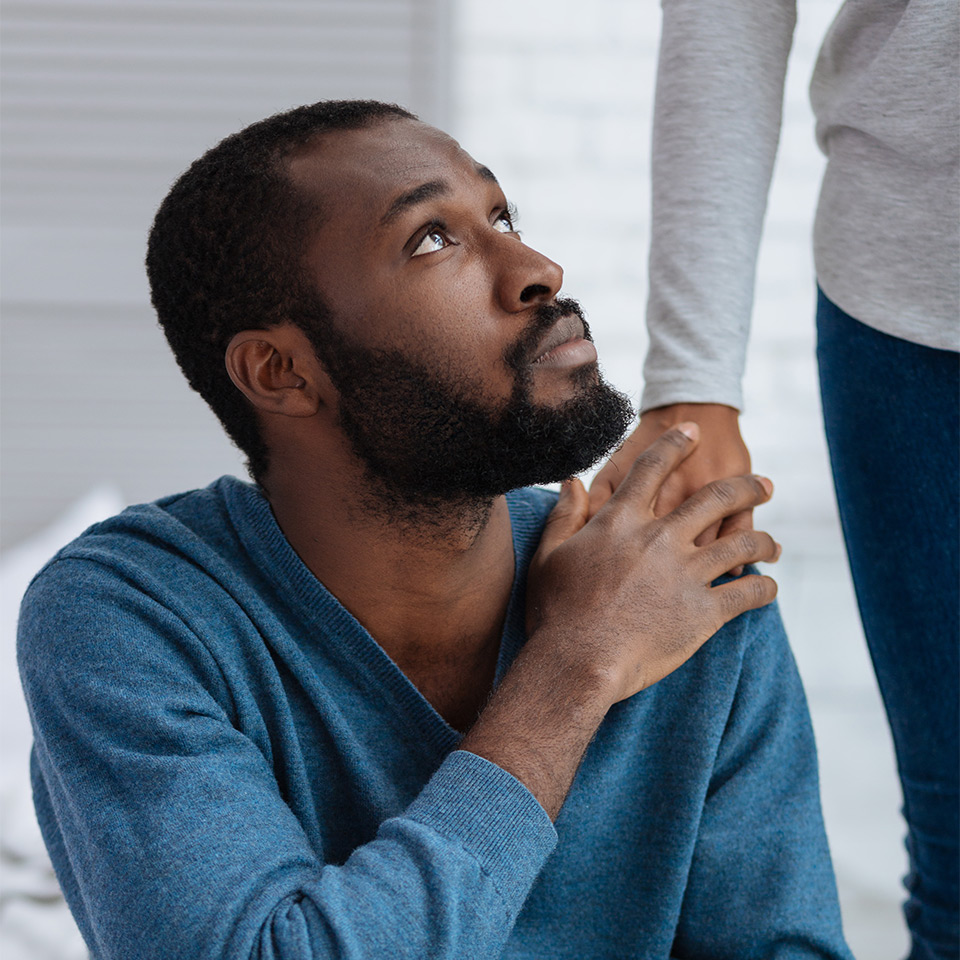 Man looking up to a woman, her hand rests on his shoulder in support