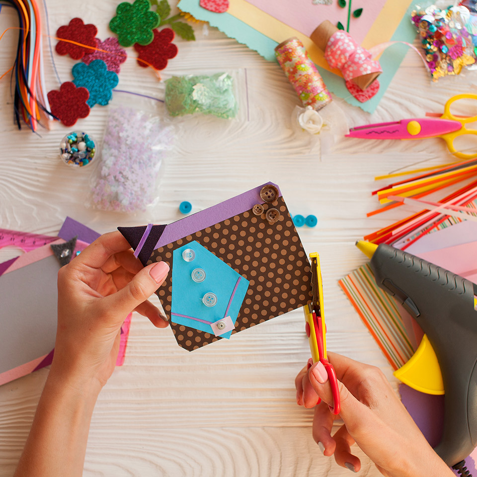 Pair of hands crafting a handmade card, surrounded by crafting materials and tools