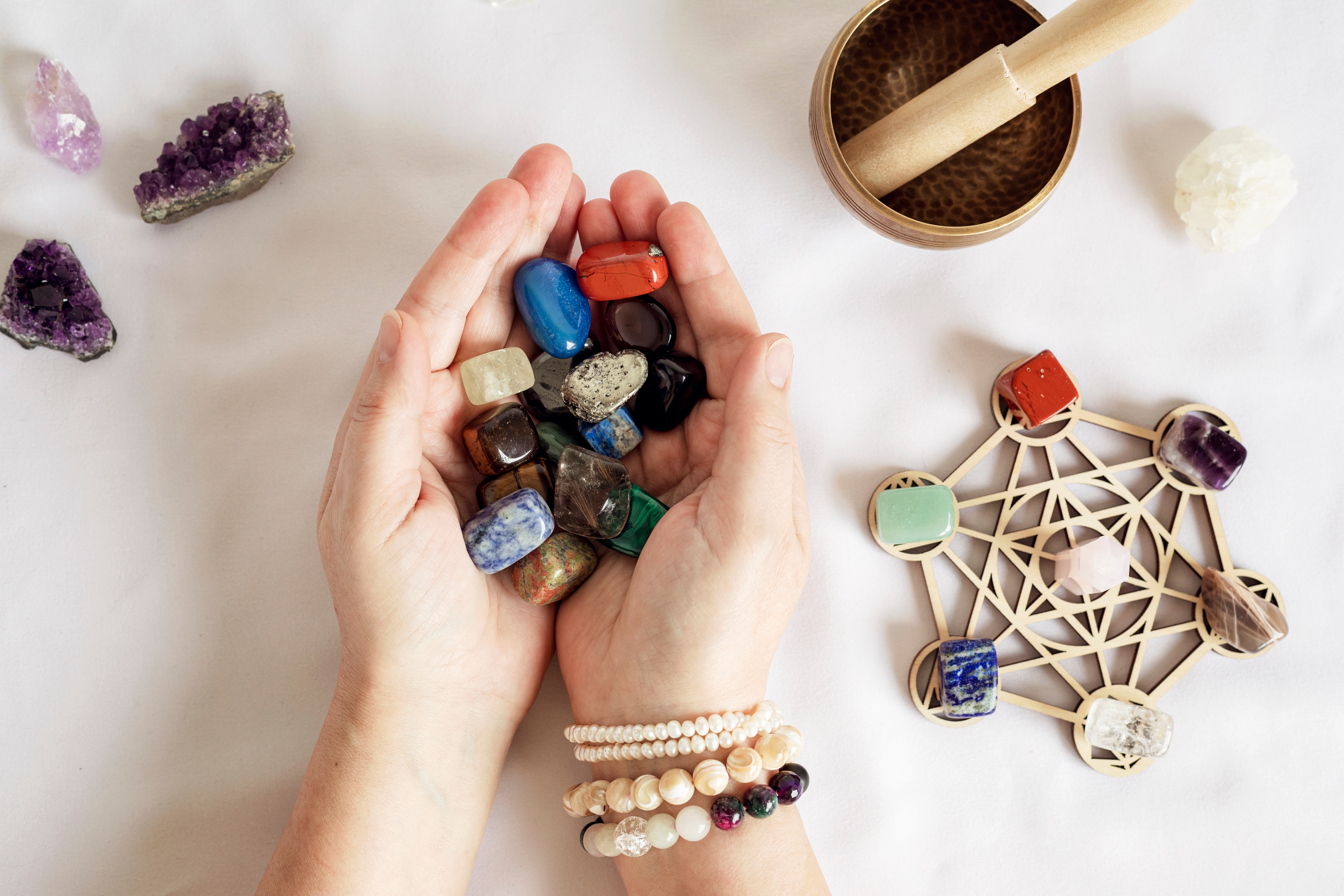 Someone holding a selection of crystals in their hands with a crystal grid to the right of them