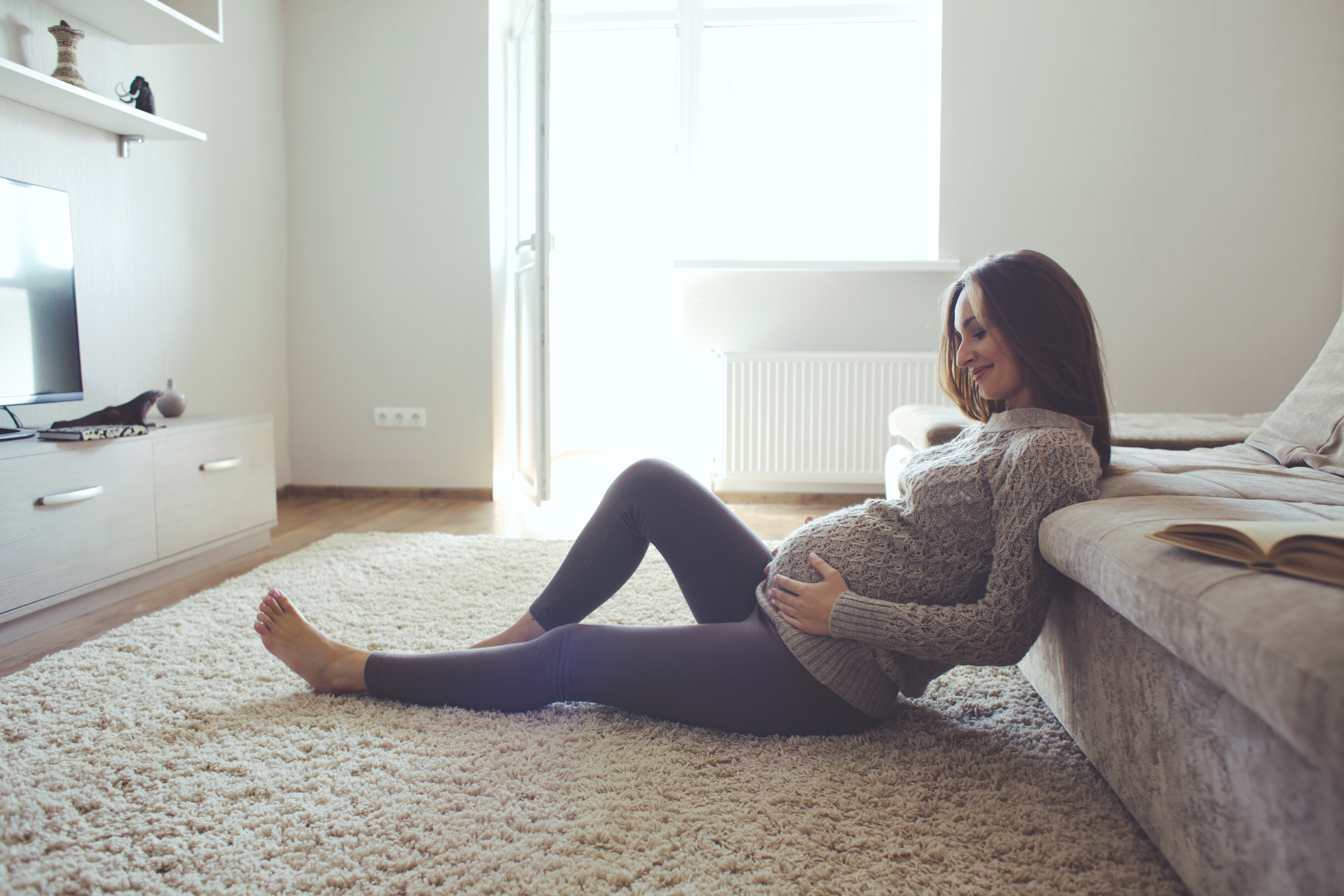 Relaxed smiling pregnancy woman sitting on the floor