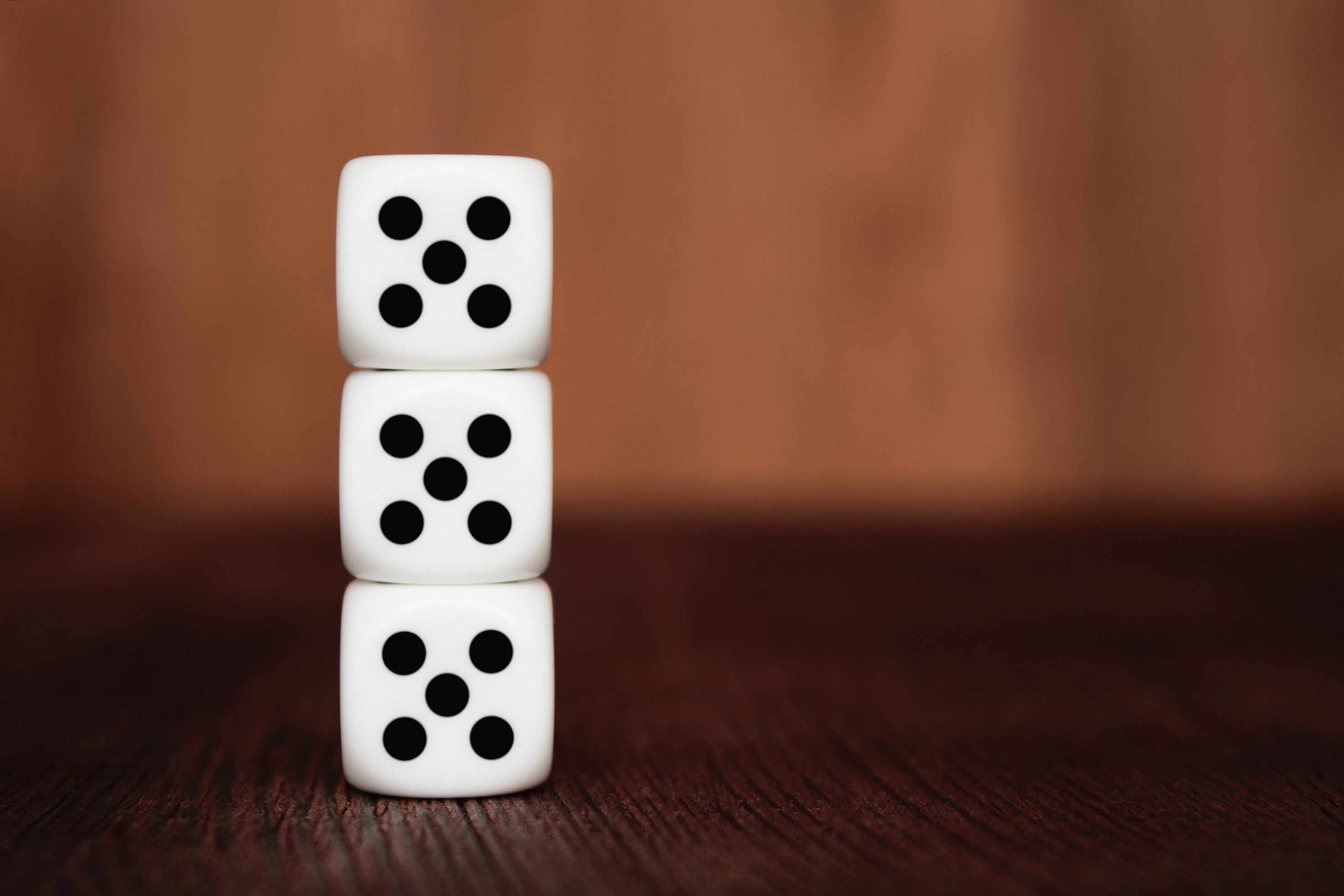 Three dice stacked on top of one another all showing the number 5