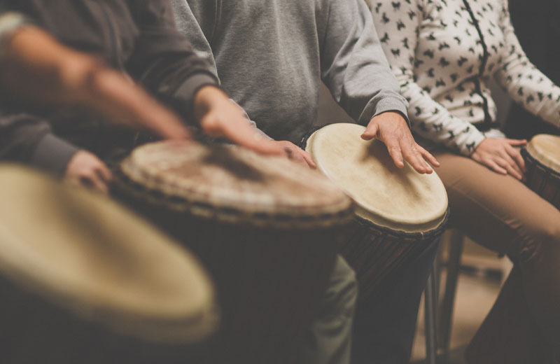 A group of people engaging in music therapy with drums.