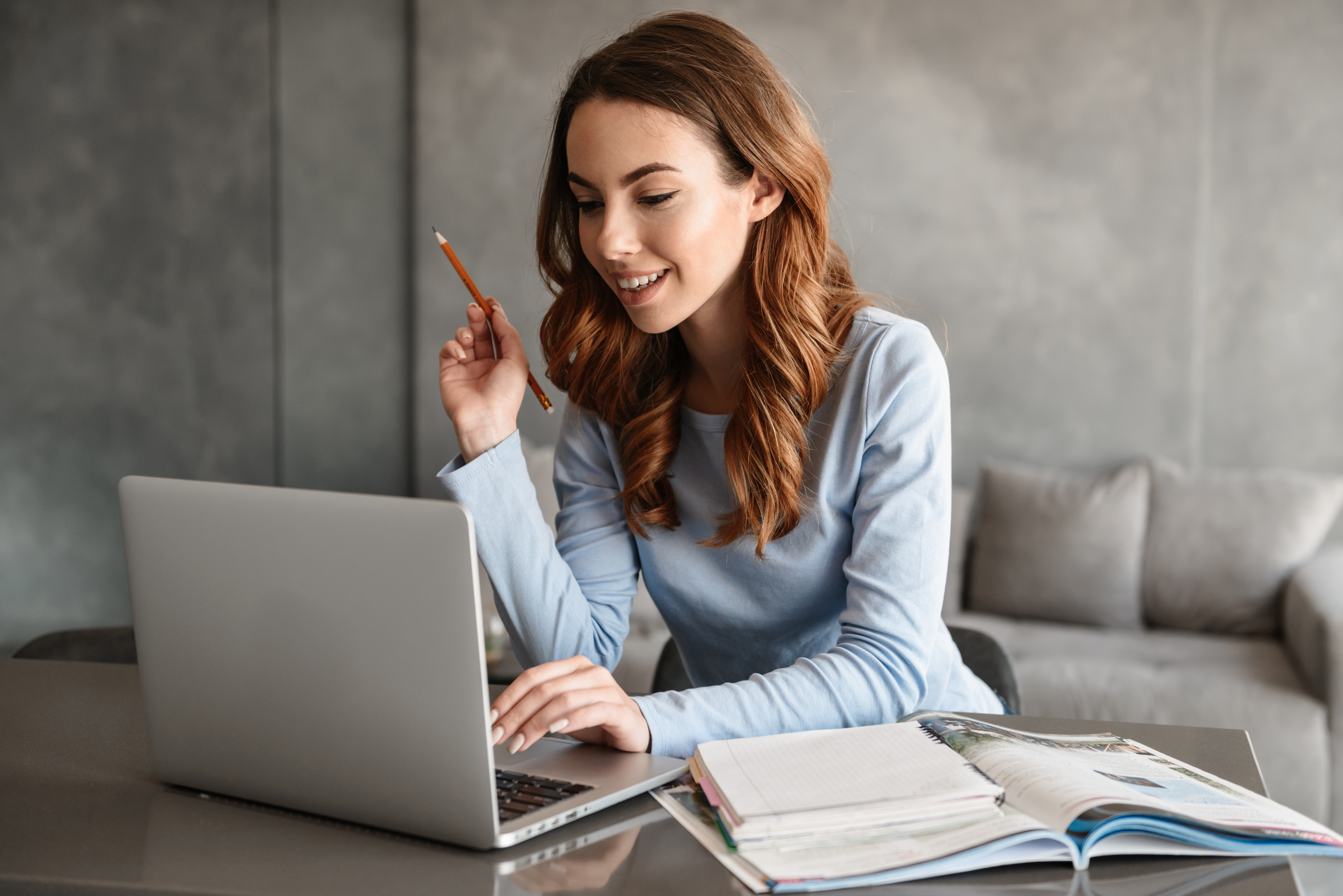 Happy woman working on her laptop with notebooks