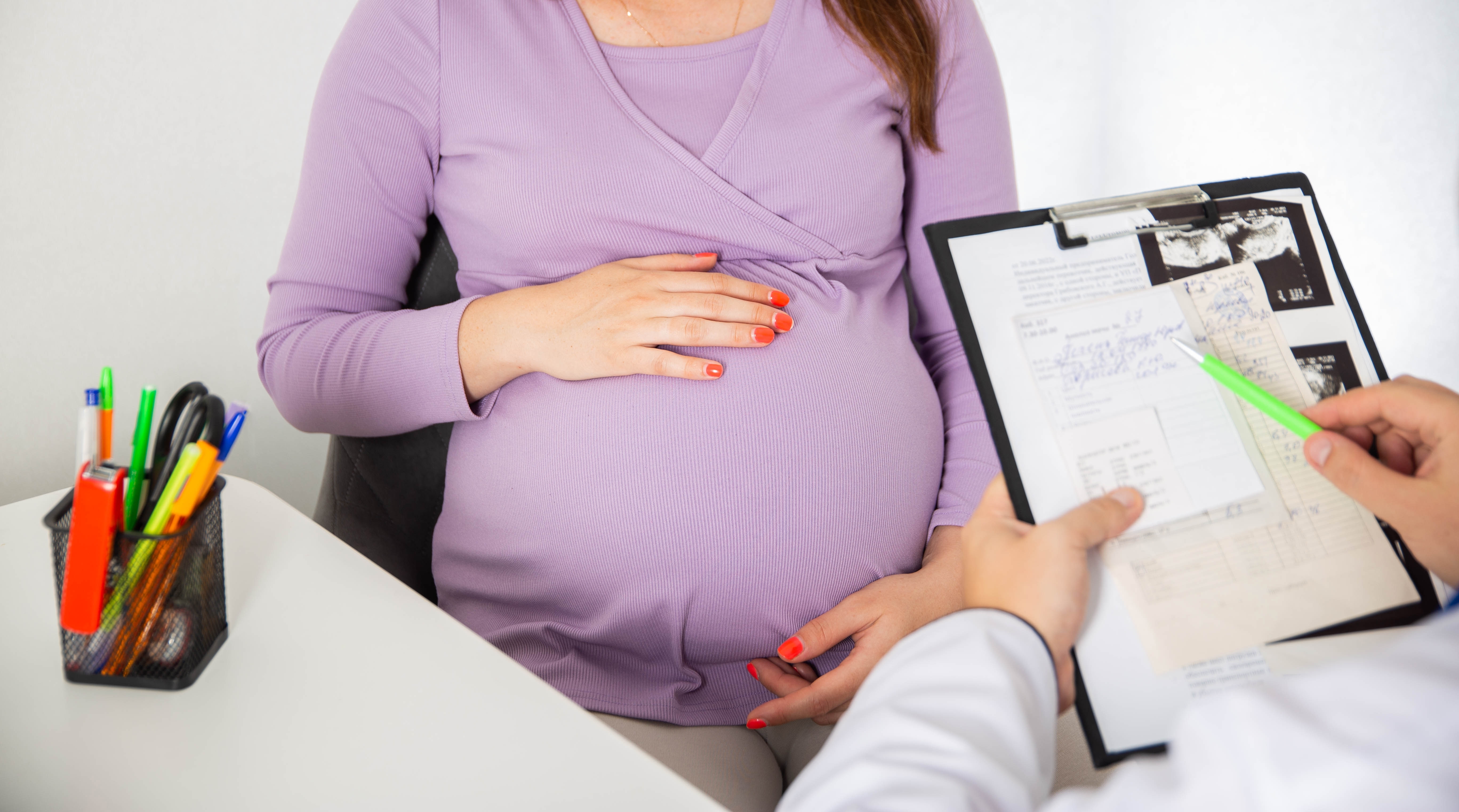 A pregnant woman sat with a doctor going through notes