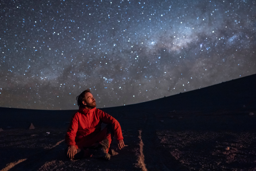 A man sat beneath the stars looking at constellations