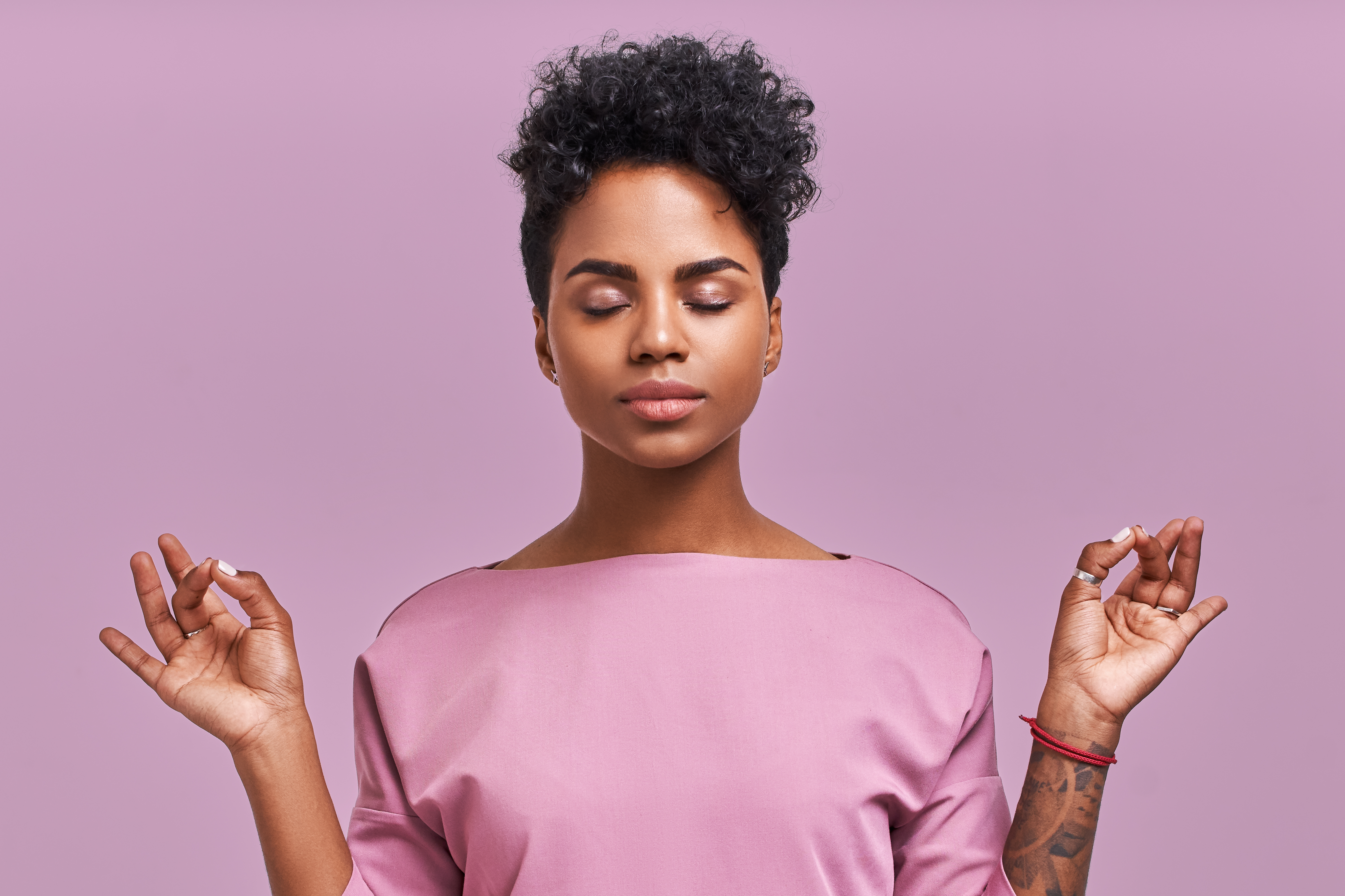 A woman with her eyes closed and her thumb and forefinger touching