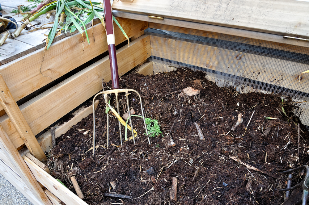 An open compost bin with a garden fork