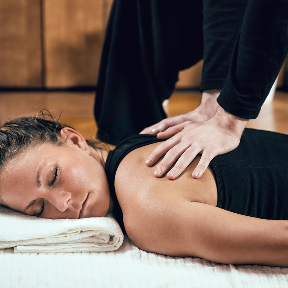 Shiatsu practitioner applying pressure on vital meridian points with two thumbs on the foot of a client