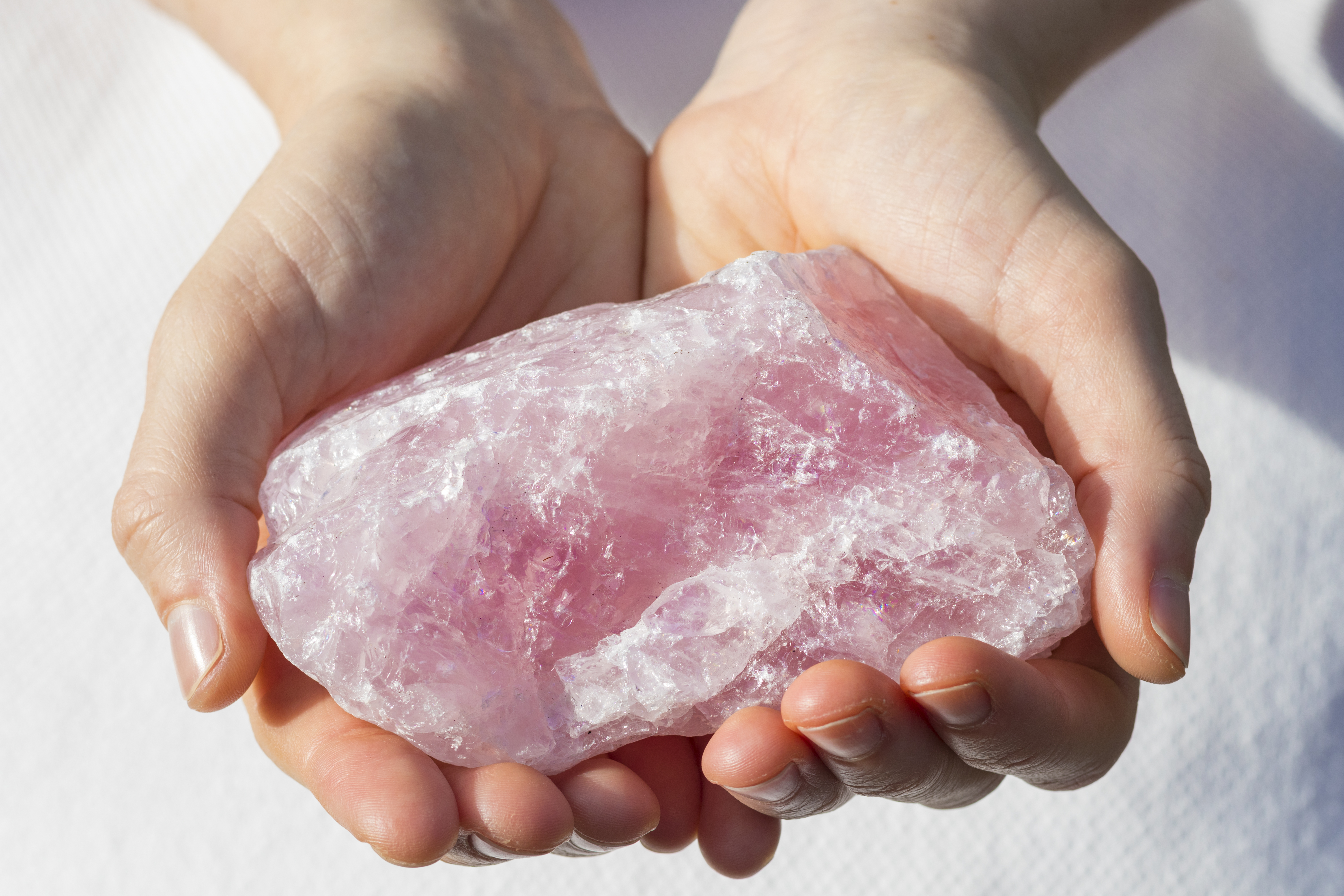 Someone holding a big chunk of rose quartz in their hands