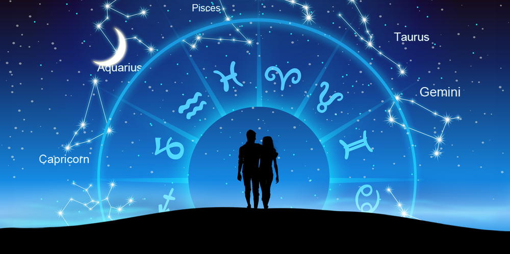 Silhouette of a couple with a Zodiac wheel in front of them