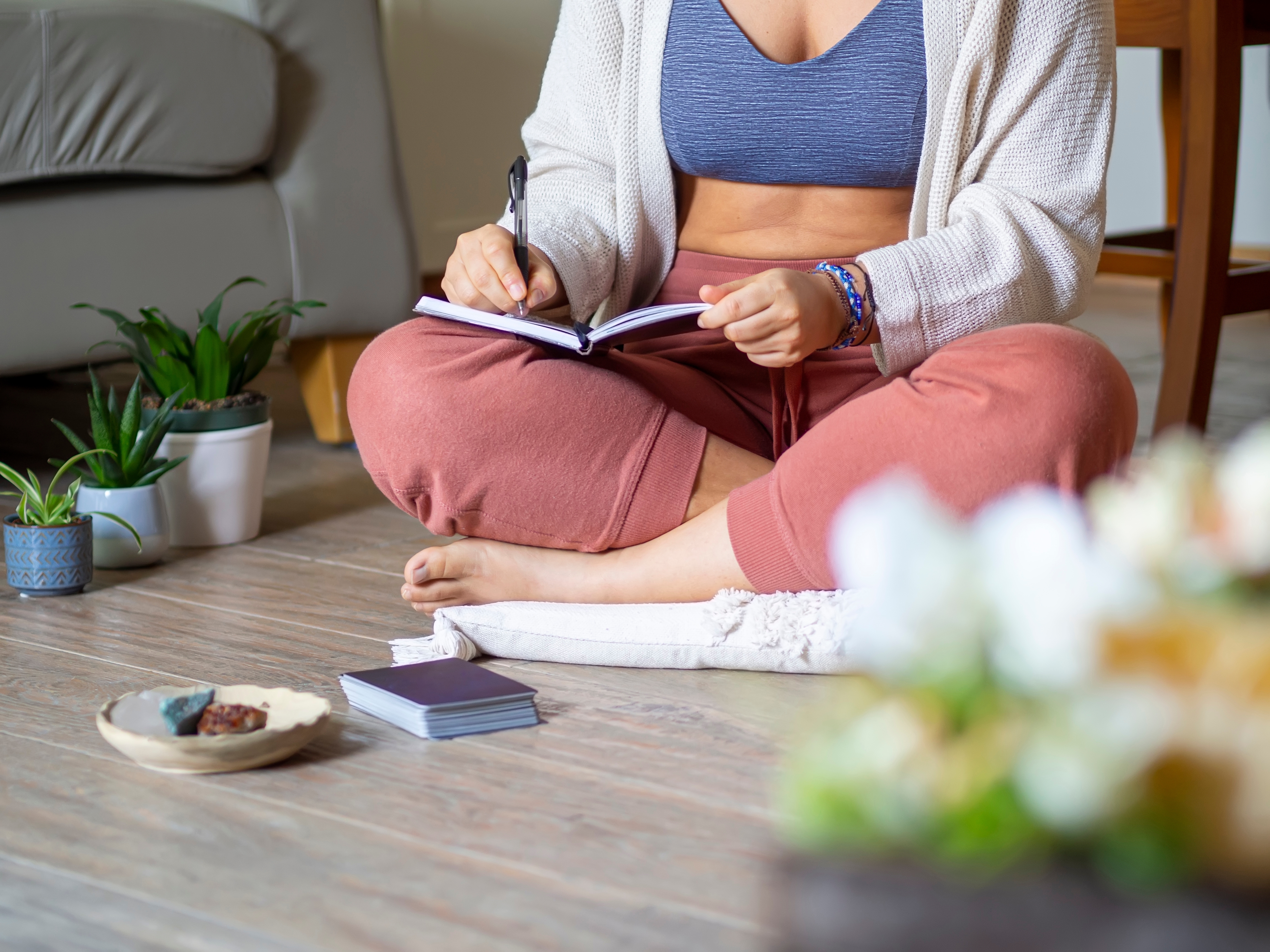 Someone sitting cross legged on the floor writing in a journal