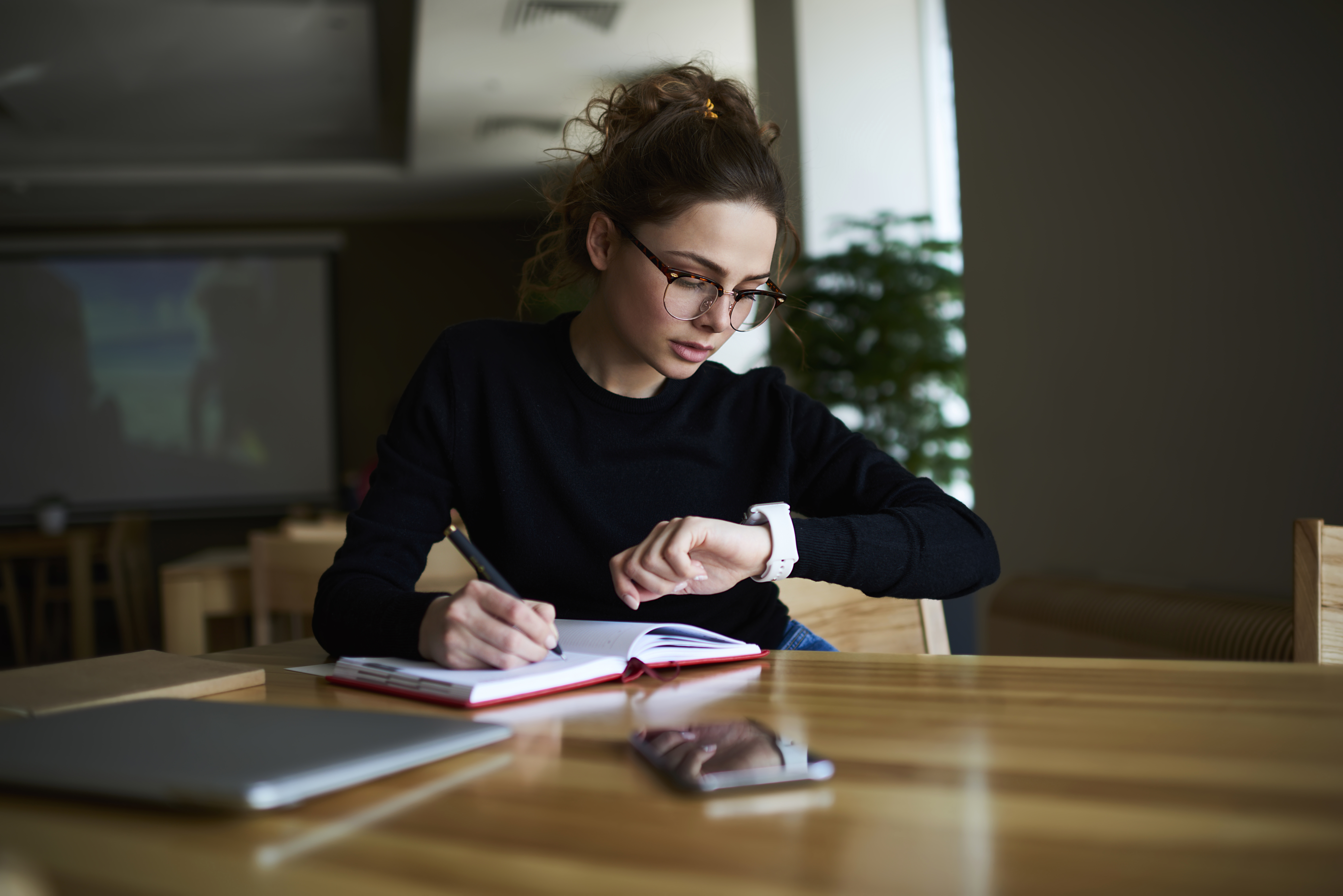 Time management, woman looking at watch as she works