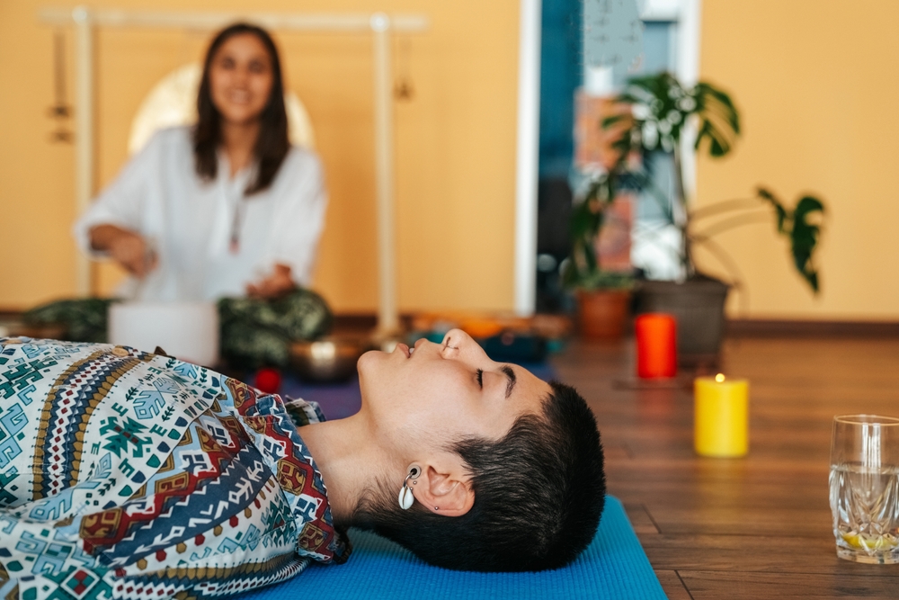 Close up of someone in a sound bath session with the instructor in the background