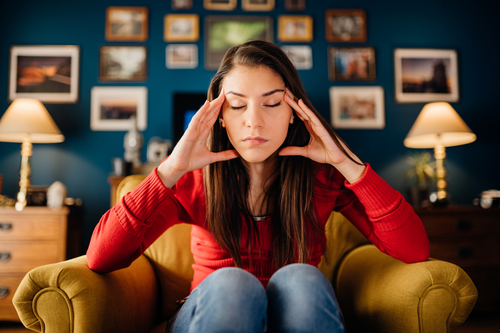 Woman sat with her eyes closed and hands on her temples