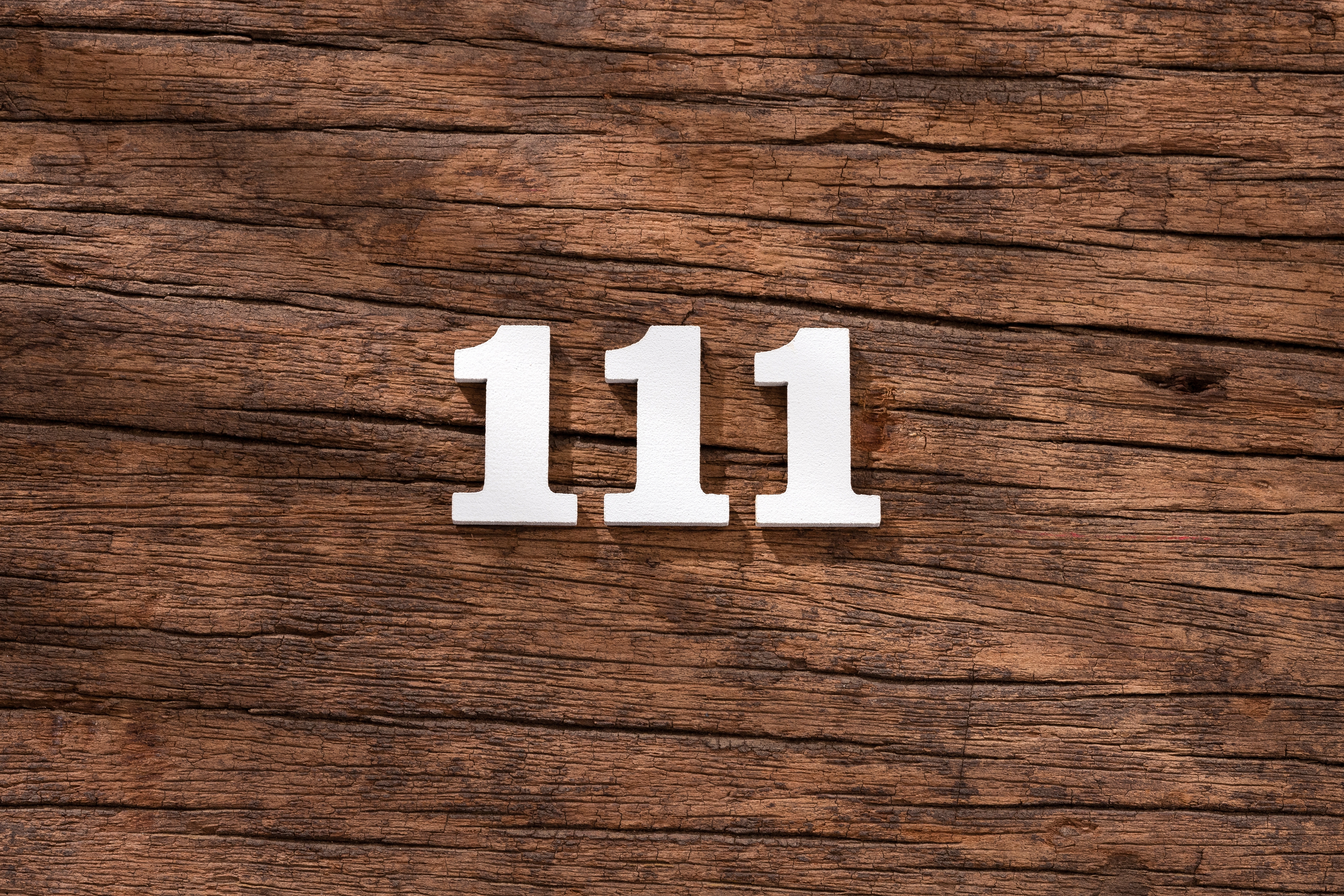111 written in white on a wooden background